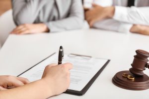 person signing a postmarital agreement in austin with spouse and lawyer in the room