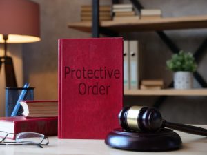 austin protective order textbook on top of a desk next to a gavel and other office supplies