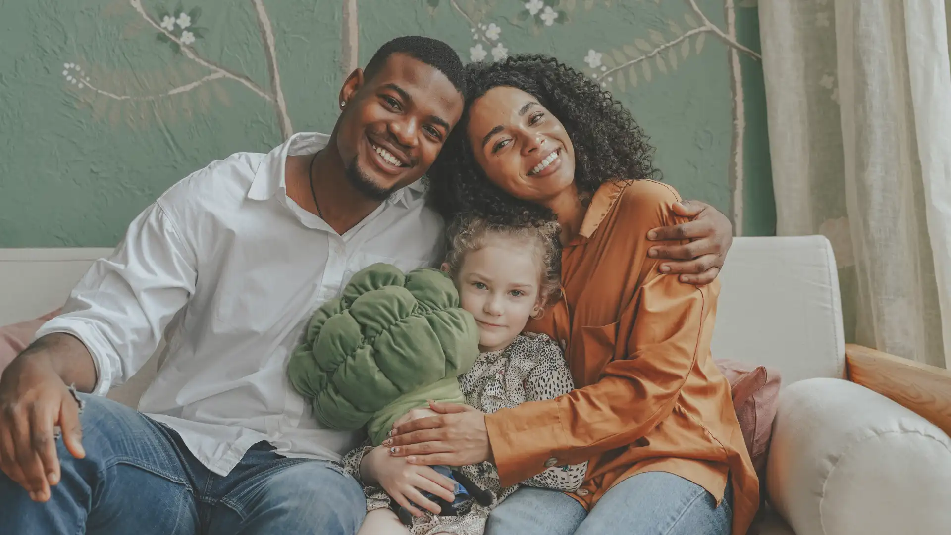 a happy couple hugging their adopted child sitting on a couch