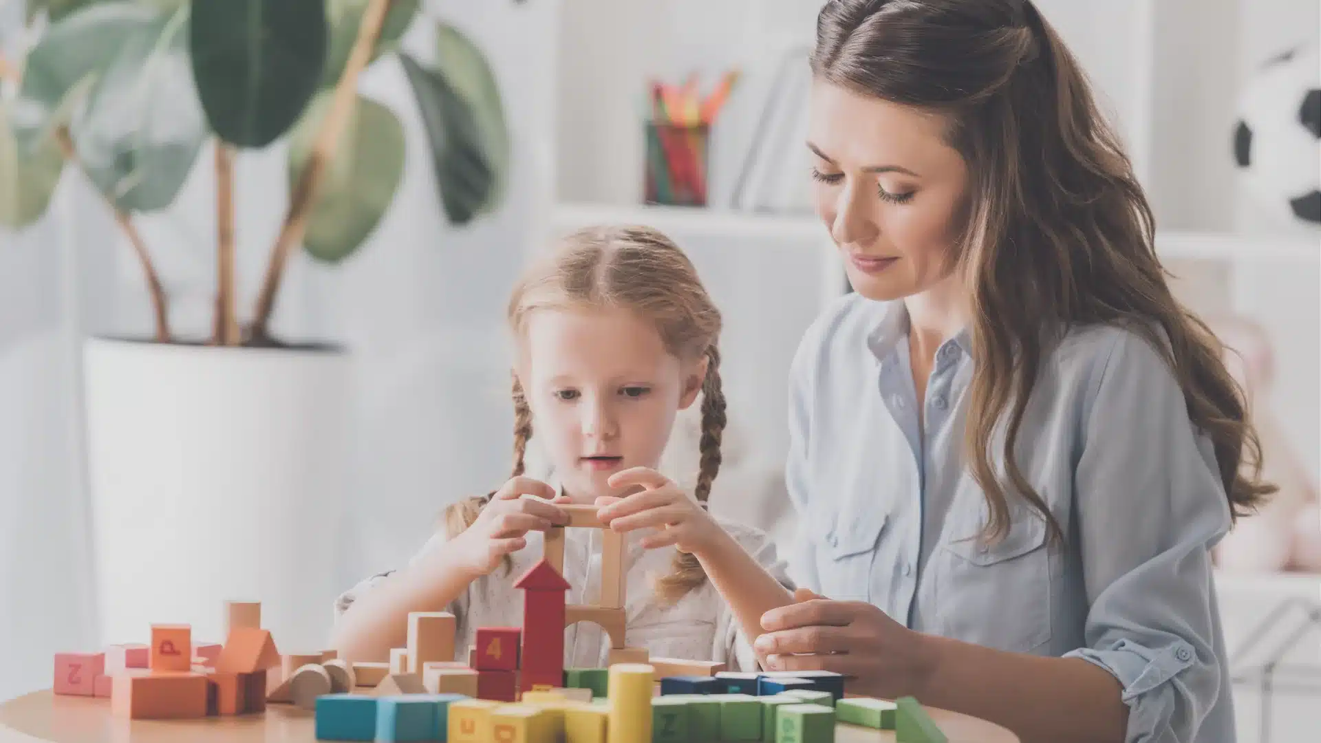 a woman and child playing toys on the table wondering if can you adopt if you have autism