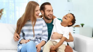 a man and woman sitting on a couch with their adopted child