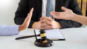 a divorce attorney with a gavel on the table between two persons talking about divorce