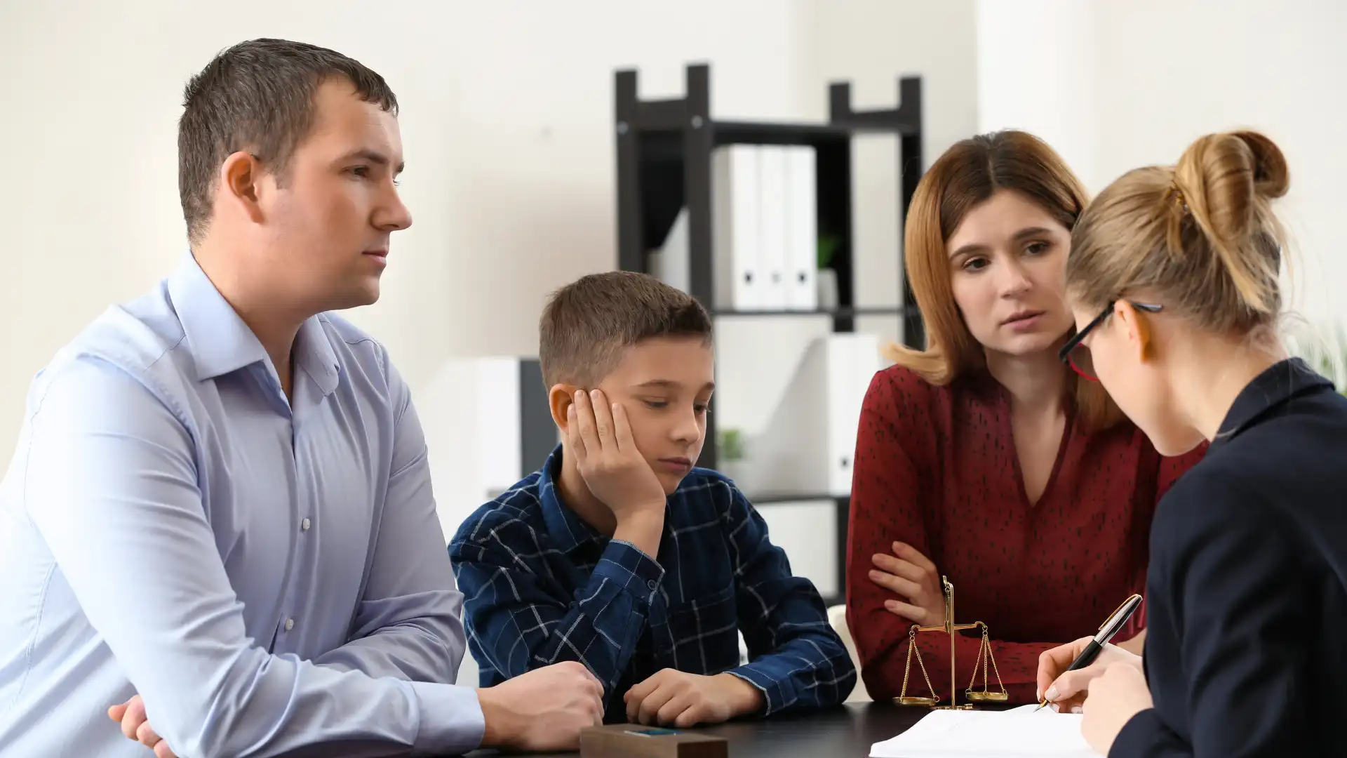 Somber boy seated between parents during legal consultation