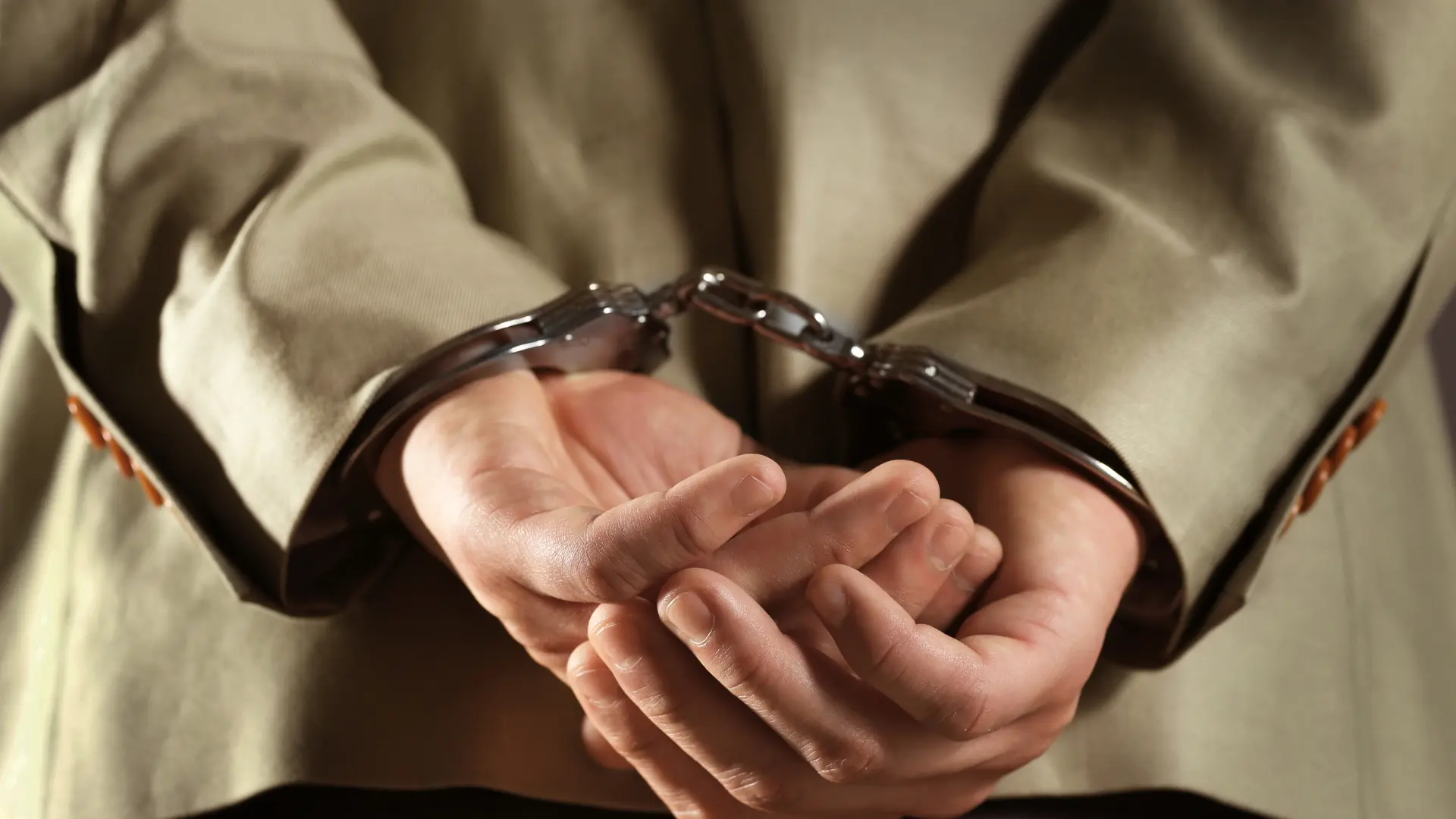 Hands cuffed in front of suited person