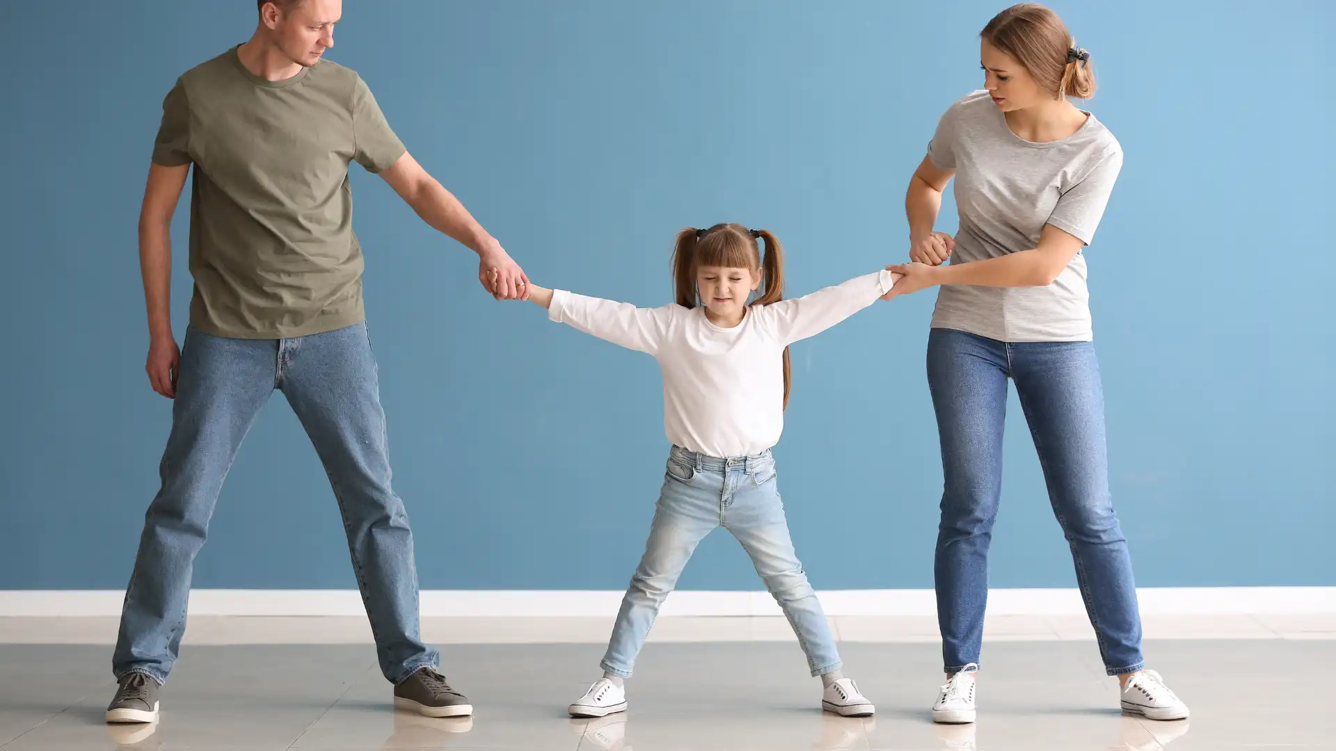 ittle girl tugged between parents holding each of her hands