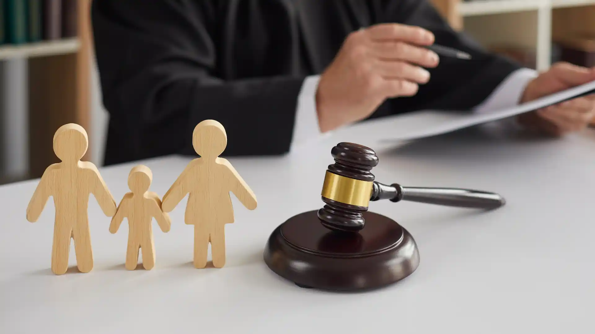 Judge at desk with gavel and wooden family figures symbolizing custody or family law