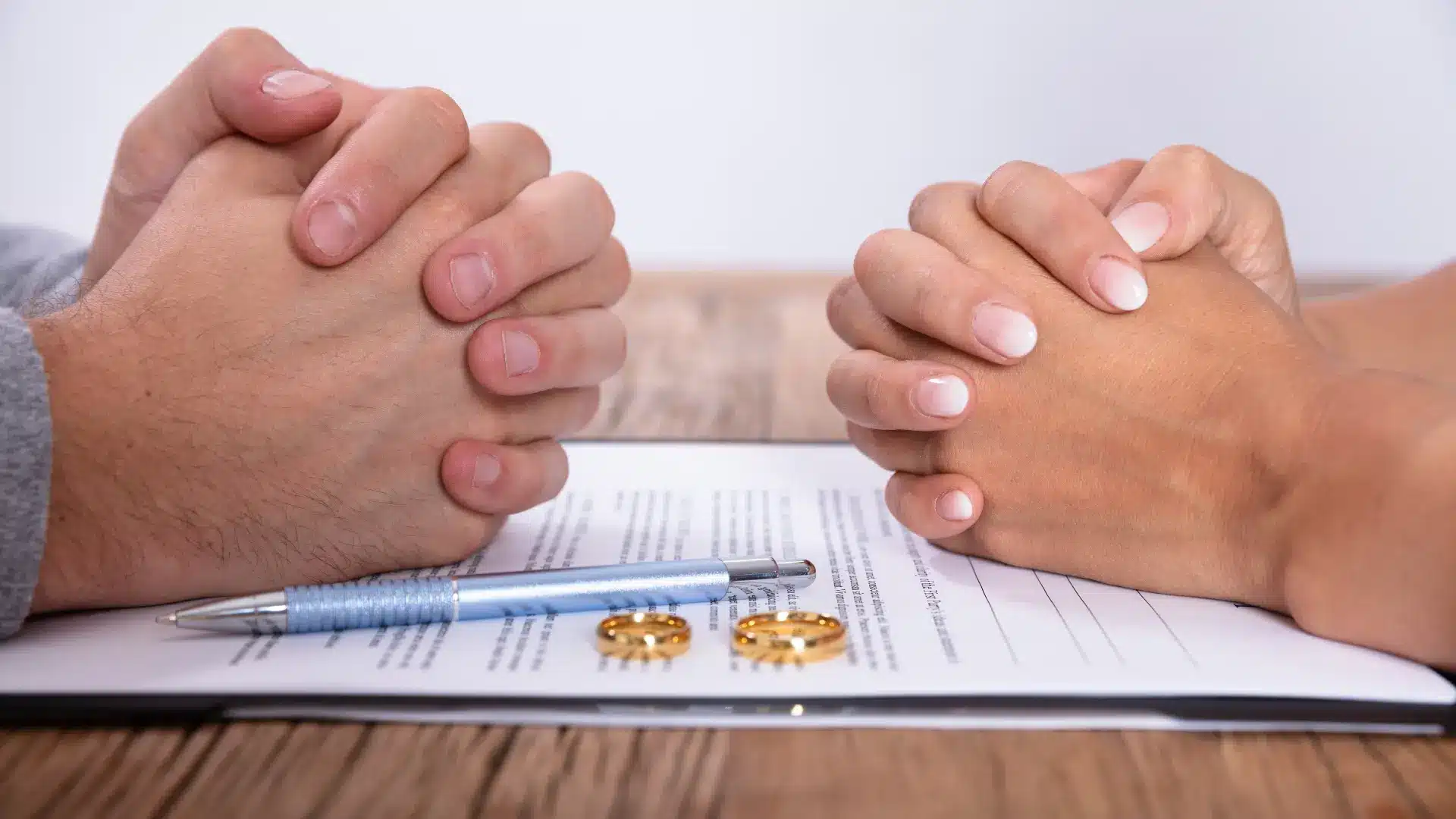 Divorcing couple with wedding rings and legal documents on the table.