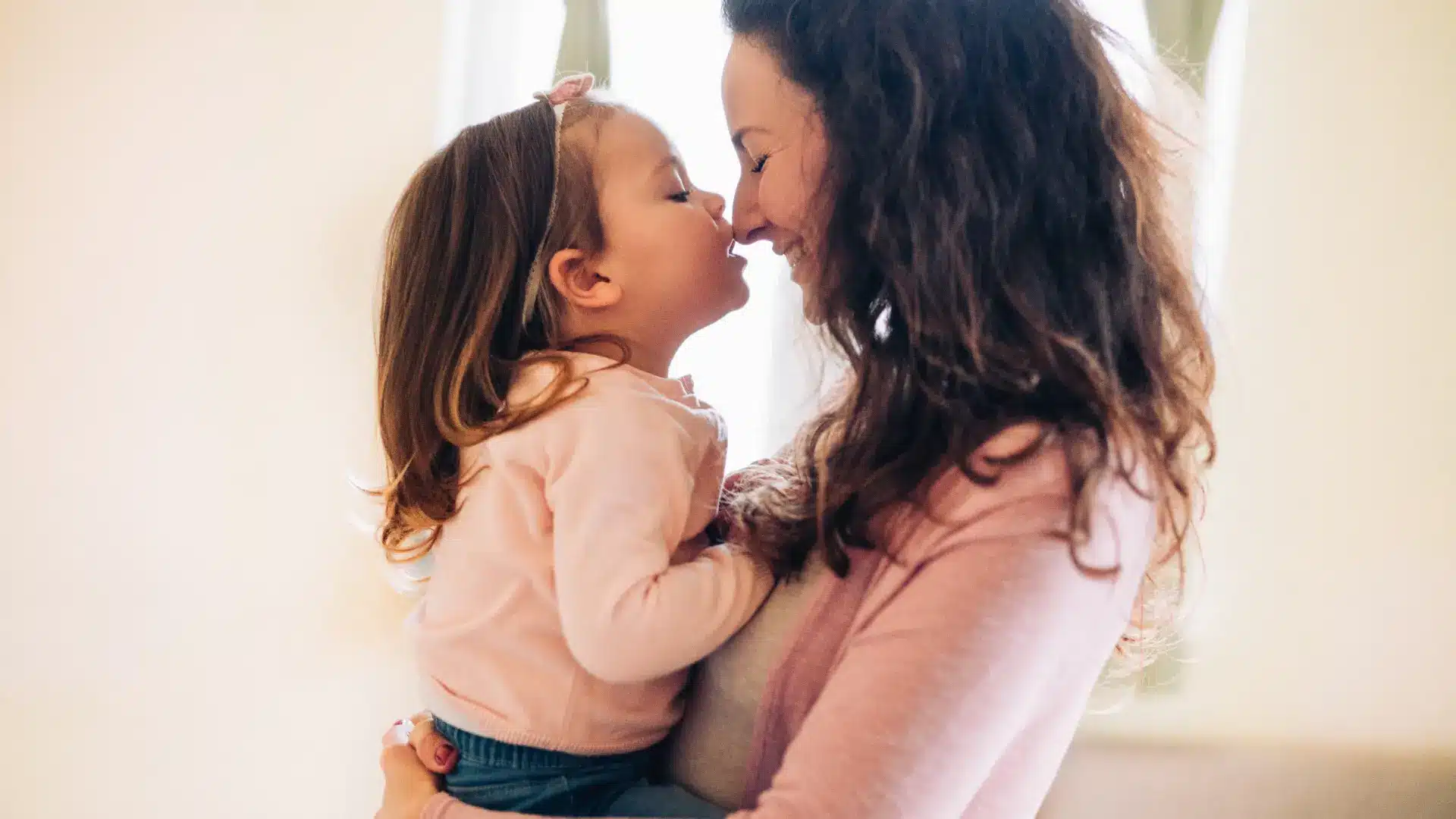 Mother and daughter sharing a tender moment, nose-to-nose.